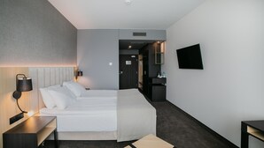 A modern hotel room with a large bed, bedside table, lamp, and a flat-screen TV mounted on the wall. - B&B HOTEL Warsaw East (Warsaw)