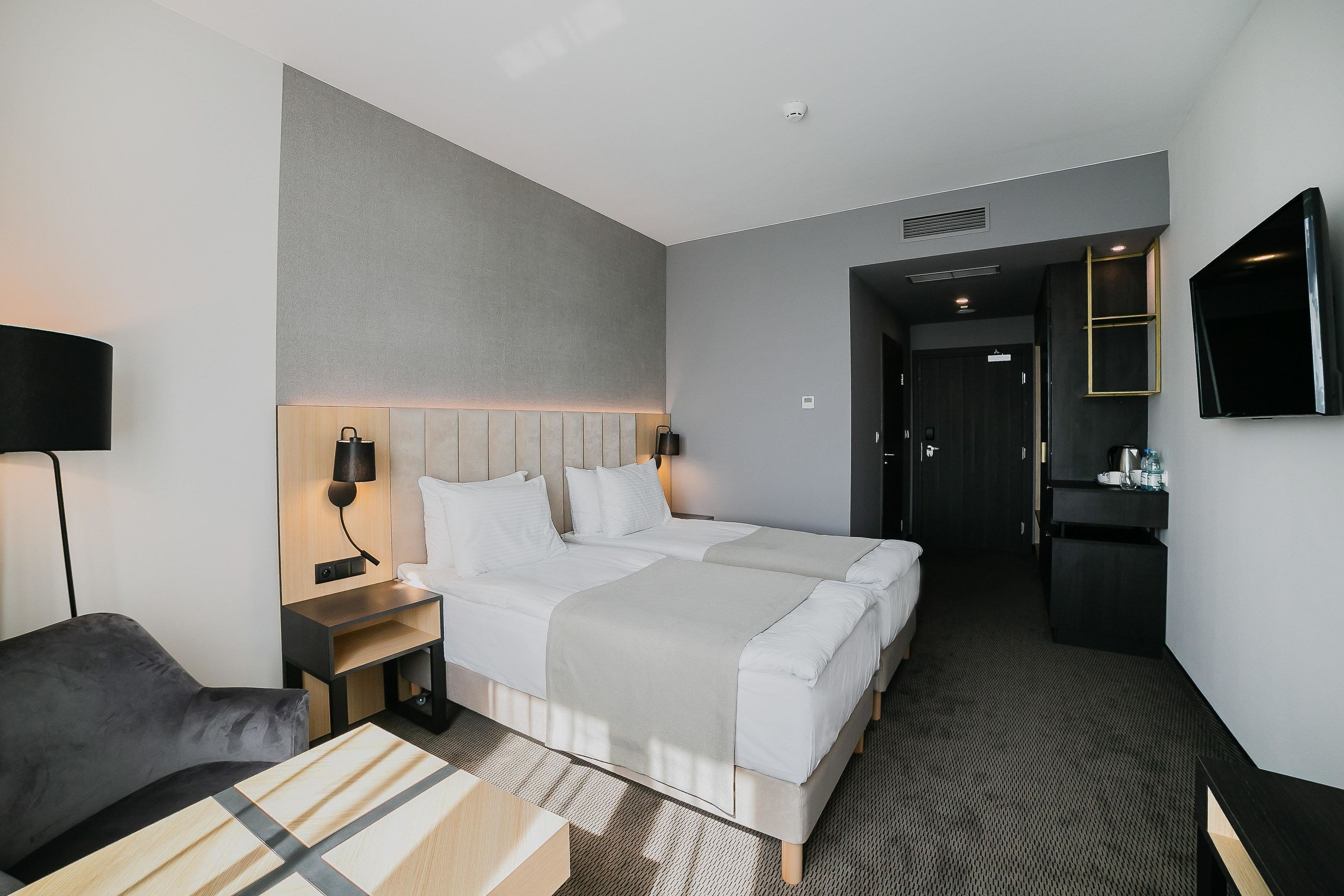 Habitación de hotel con dos camas, un escritorio, una silla, un televisor y un minibar.
