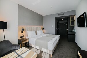 Ένα δωμάτιο ξενοδοχείου με δύο κρεβάτια, ένα γραφείο, μια καρέκλα, μια τηλεόραση και ένα μίνι μπαρ.