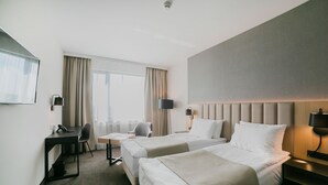 A hotel room with two beds, a desk, a chair, and a large window with curtains. - B&B HOTEL Warsaw East (Warsaw)