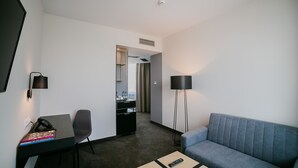 A hotel room with a desk, chair, sofa, and a TV. - B&B HOTEL Warsaw East (Warsaw)