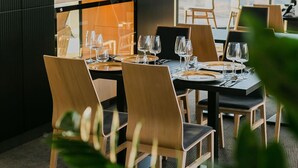 A restaurant with a modern interior, featuring wooden chairs and tables, large windows offering a view of the outside. - B&B HOTEL Warsaw East (Warsaw)