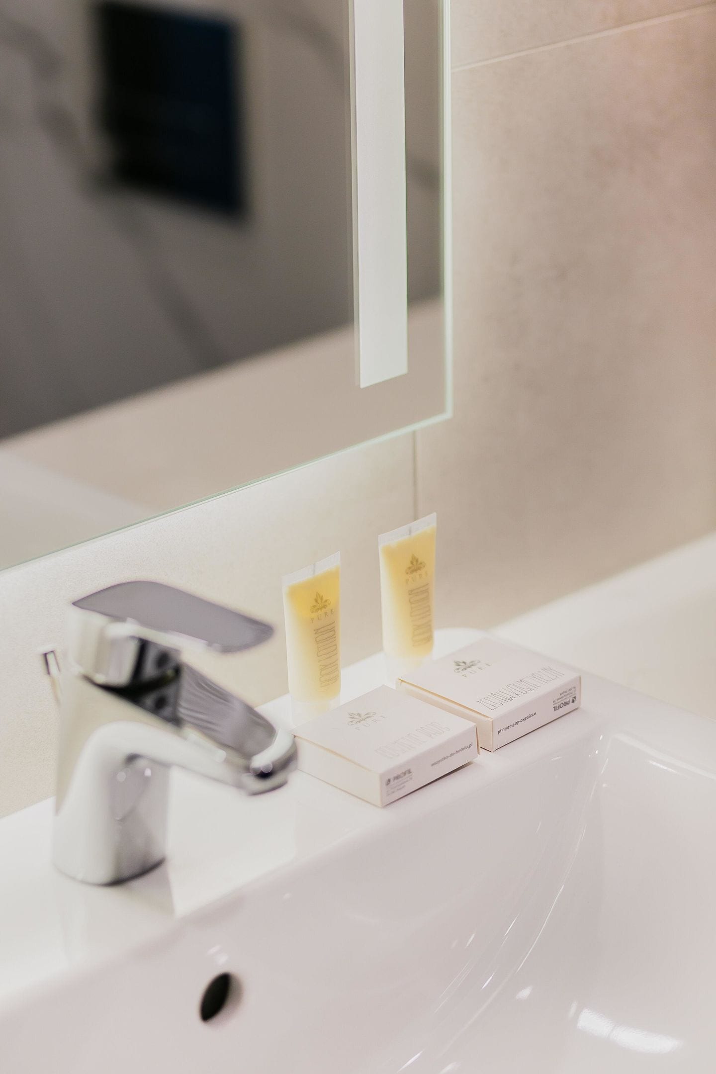 A bathroom sink with a mirror, a faucet, and two toiletry boxes.