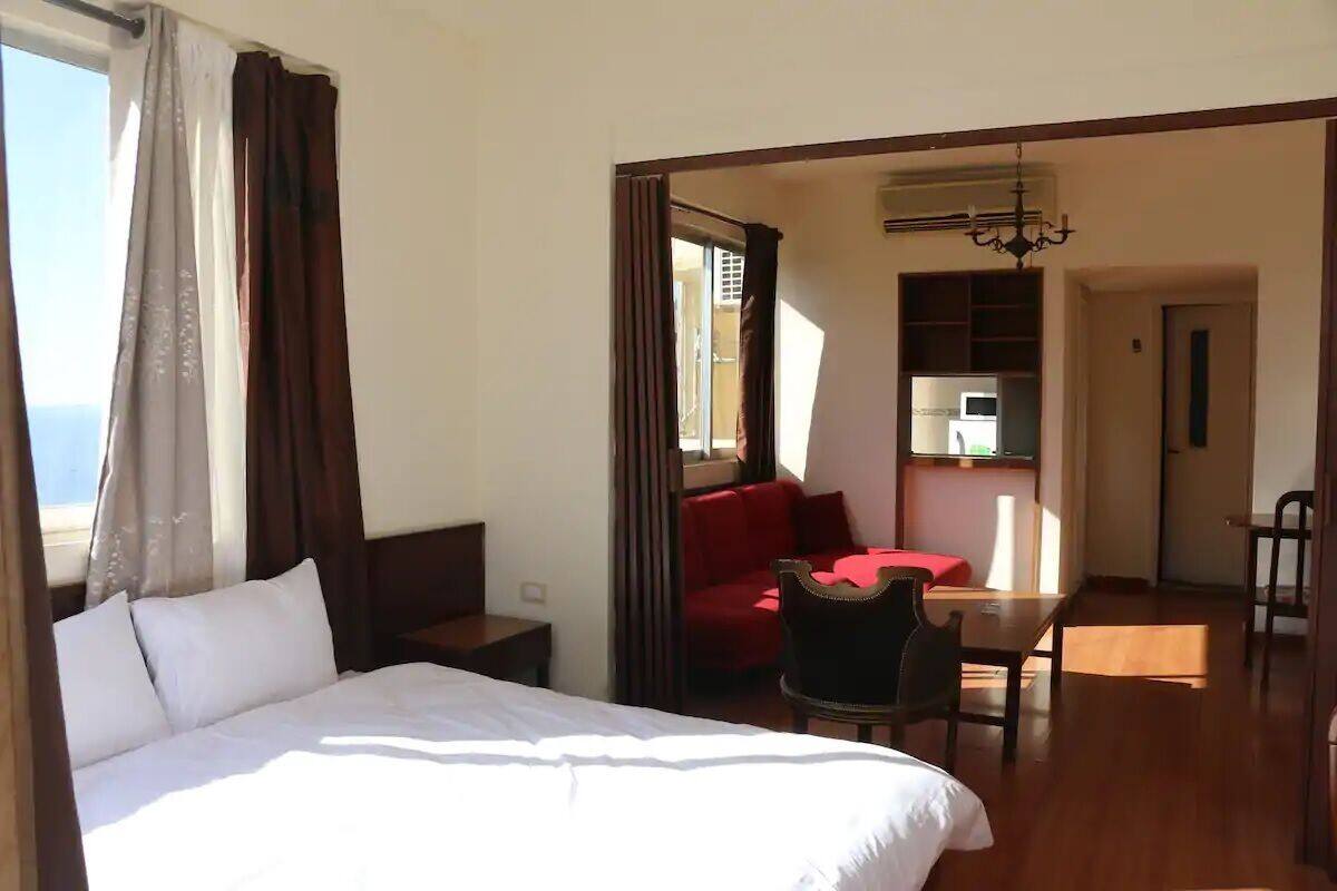 Une chambre d’hôtel avec un lit, un bureau, une chaise et une vue sur la mer.