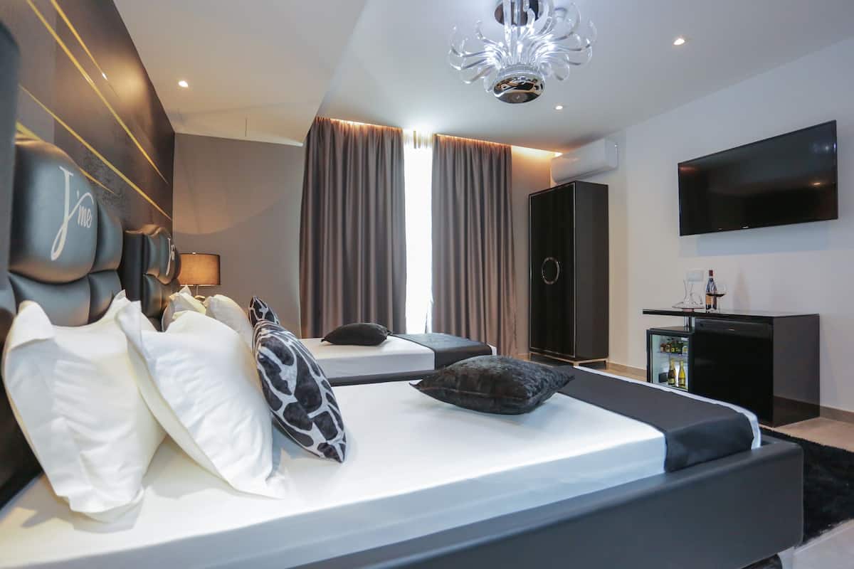 Ein modernes Hotelzimmer mit einem großen Bett, einem Flachbildfernseher, einer Minibar und einem großen Fenster mit Vorhängen.