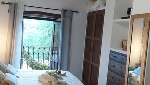 Ein Schlafzimmer mit einem großen Bett, einem Holzschrank, einem Balkon und einem Spiegel.