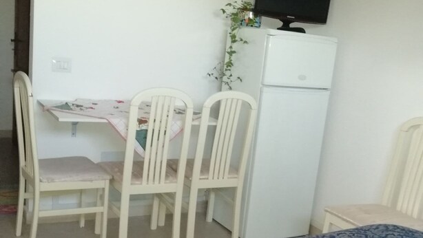 A room with a bed, a desk, and two chairs. There is a television on a stand above the desk. - PALAZZINA LA TORRE VIA CRFINUIM 4 (L'Aquila)