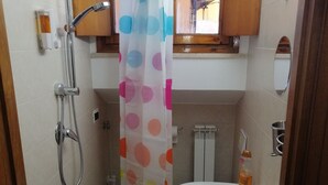 A bathroom with a shower, a sink, a toilet, and a blue mat. - PALAZZINA LA TORRE VIA CRFINUIM 4 (L'Aquila)