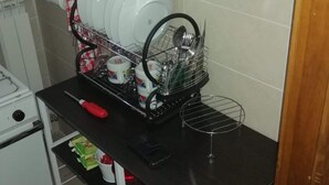 A kitchen with a dish rack holding plates and utensils, a stove, and a hanging pot rack. - PALAZZINA LA TORRE VIA CRFINUIM 4 (L'Aquila)