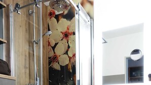 A modern bathroom with a glass shower enclosure, a white toilet, a wooden vanity with a sink, and a mirror above the sink.