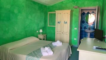 A room with two beds, a desk, a mirror, and a door with a blue-tiled window.