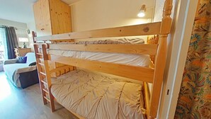 A bunk bed with a wooden ladder, a small wooden cabinet above it, and a bed with a white mattress. - Charming Studio, Ski-In/Out, Sleeps 4, Balcony View, Parking, Near Village Center (Le Grand-Bornand)