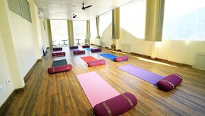 Une pièce spacieuse avec de grandes fenêtres, des tapis de yoga et des blocs disposés pour un cours de yoga.