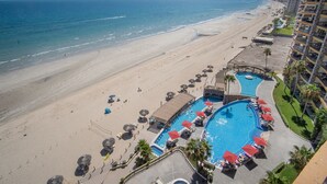 Een resort met een groot zwembad, een strand en uitzicht op de oceaan.