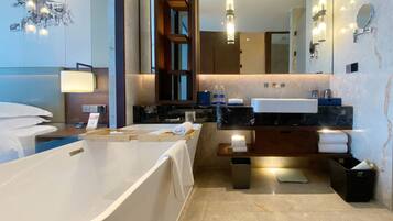 A modern bathroom with a bathtub, a vanity with a mirror, and a shower area.
