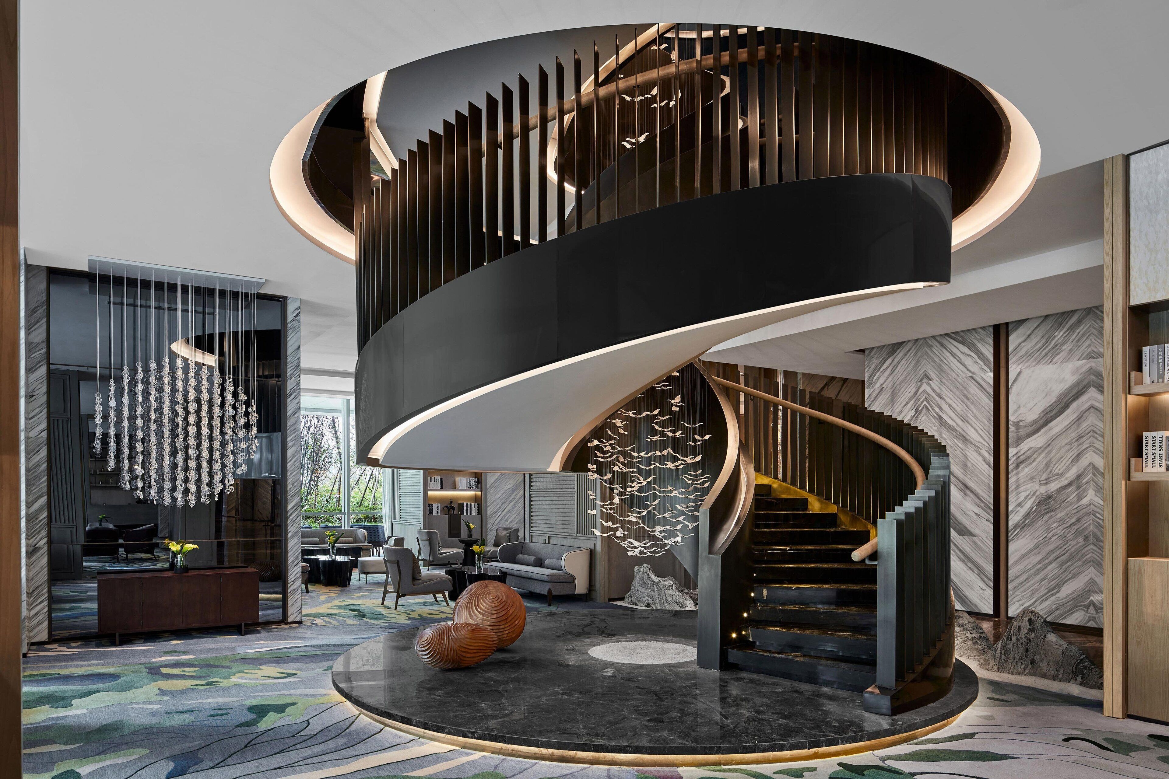 Un interior moderno con una escalera de caracol, una mesa redonda para comer y una zona de estar con una alfombra original.