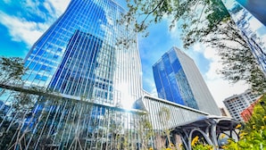 Un quartier urbain moderne, avec de hauts immeubles aux façades vitrées et une promenade piétonne.