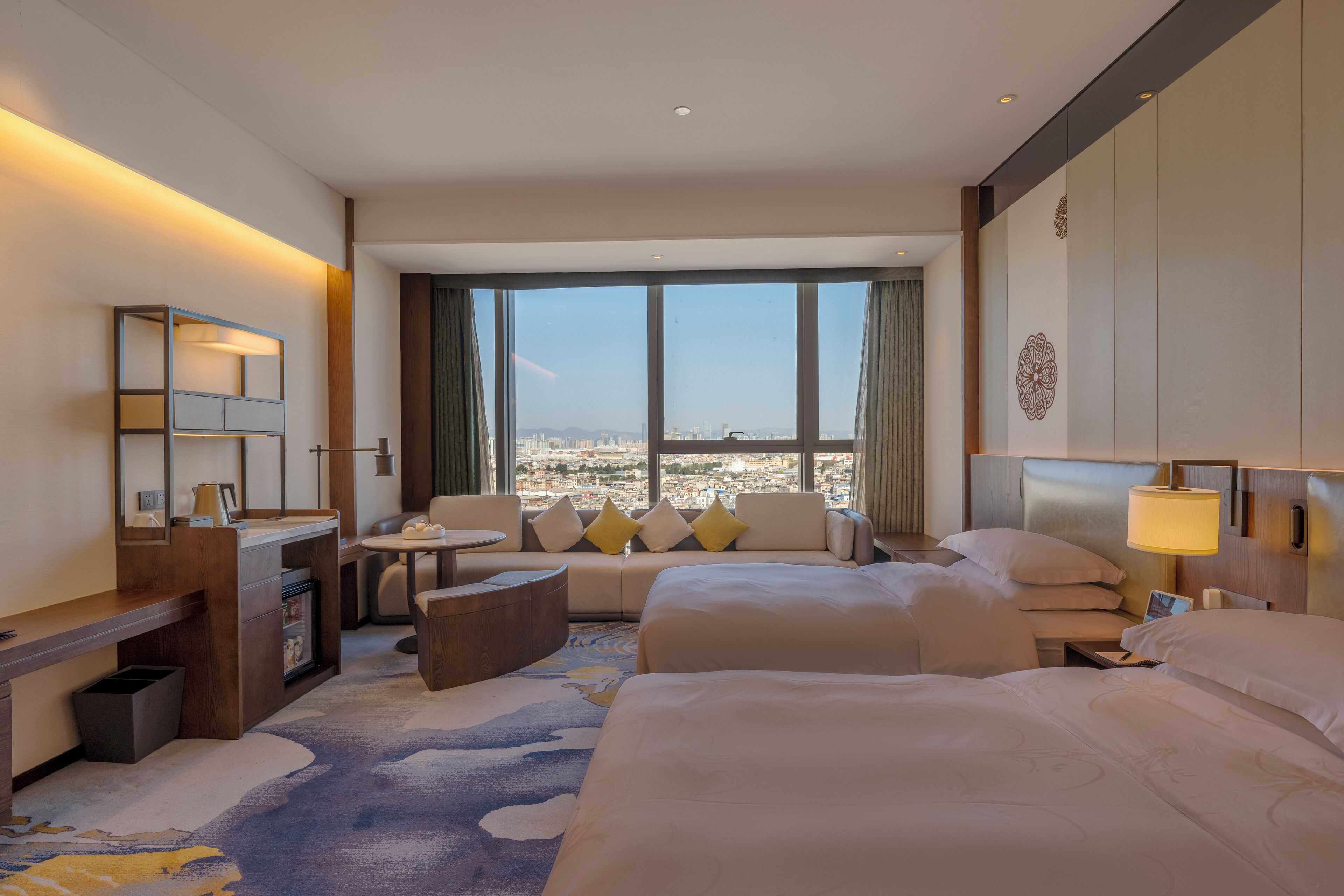 Une chambre d’hôtel avec un grand lit, un canapé, un bureau et une vue sur la ville.