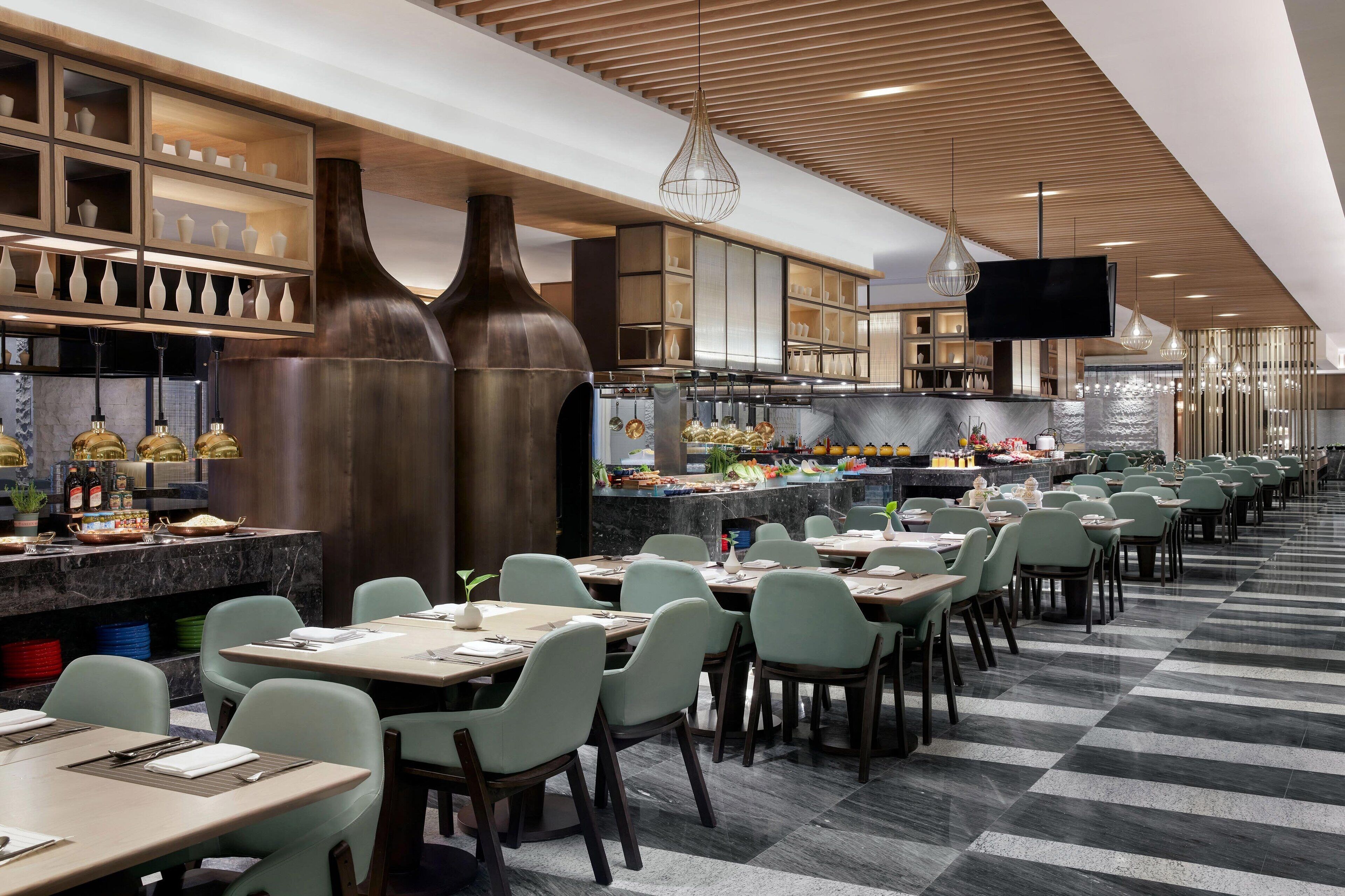 A modern restaurant with a long counter, multiple dining tables, and a variety of seating options.