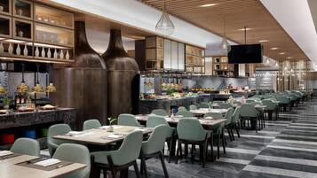 A modern restaurant with a long counter, multiple dining tables, and a variety of seating options.