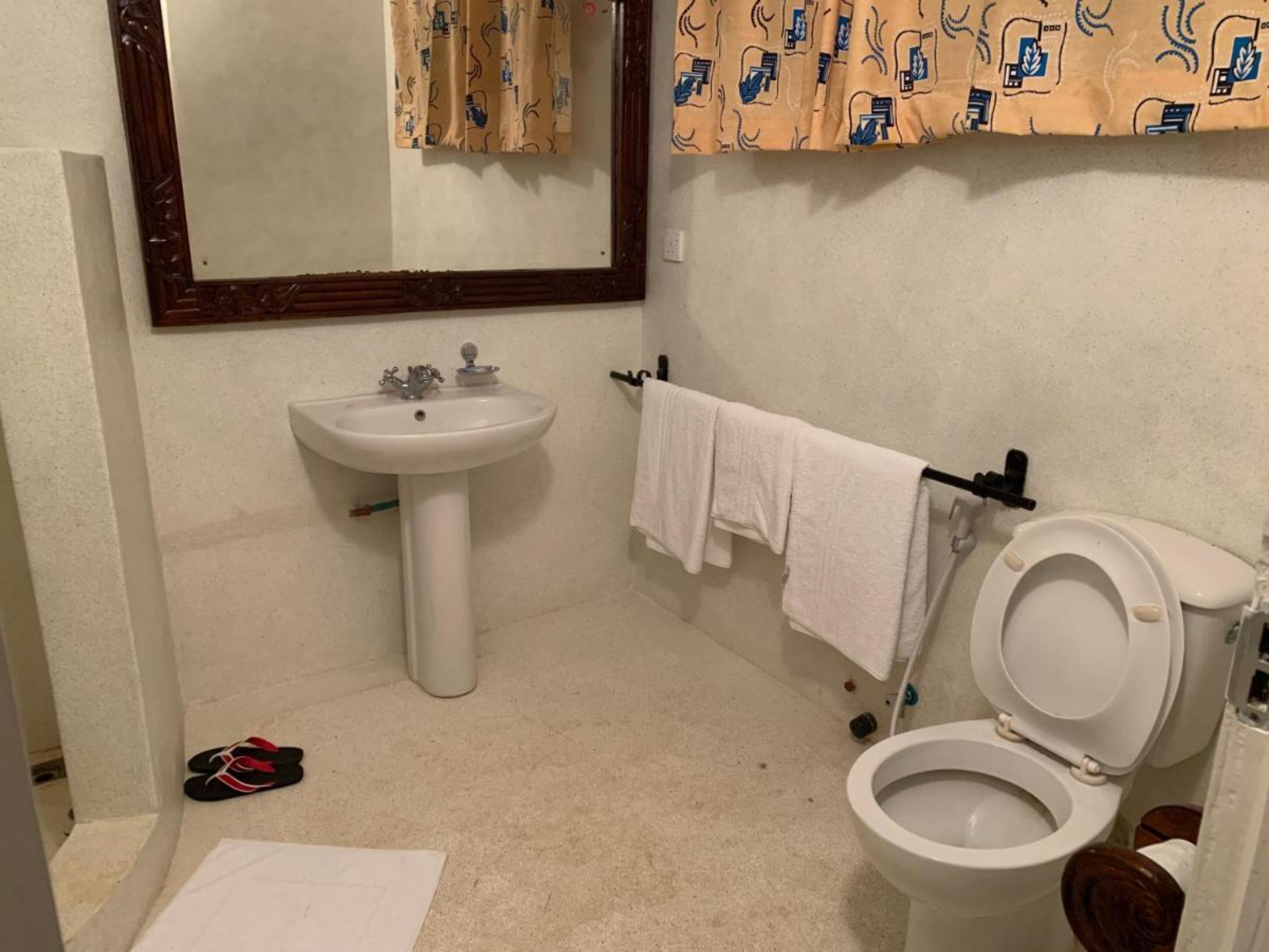 Egy fürdőszoba, amelyben fehér mosdókagyló, WC és tükör található.