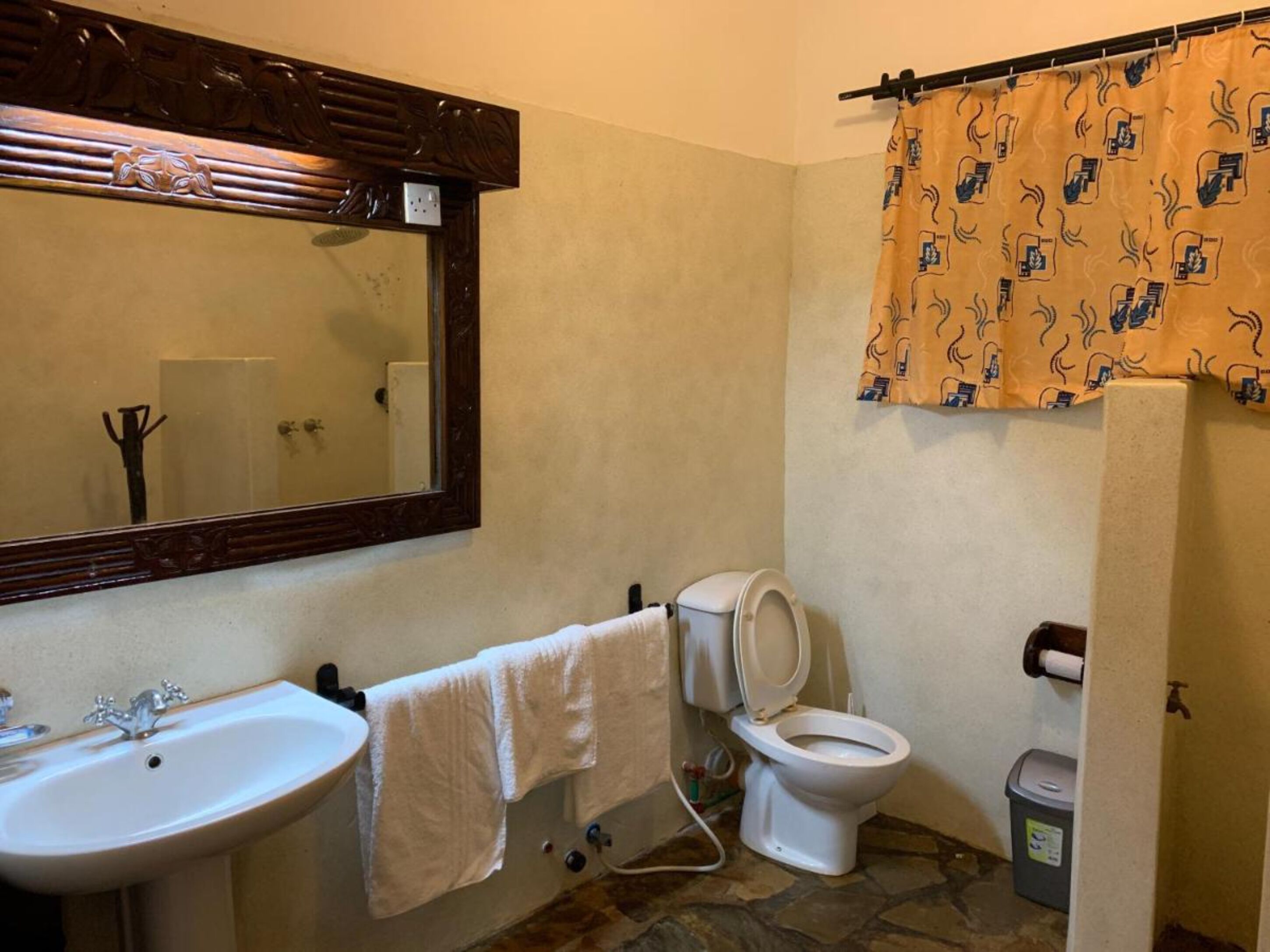 A bathroom with a sink, mirror, toilet, and shower curtain.