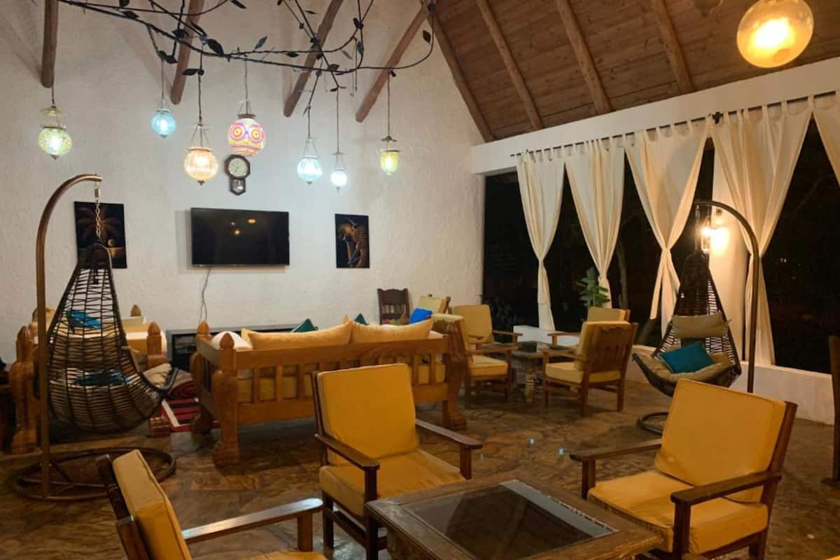 Un espacio interior acogedor con mobiliario de madera, luces colgantes y un televisor.