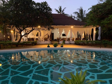 Una piscina al aire libre, sombrillas, sillones reclinables de piscina