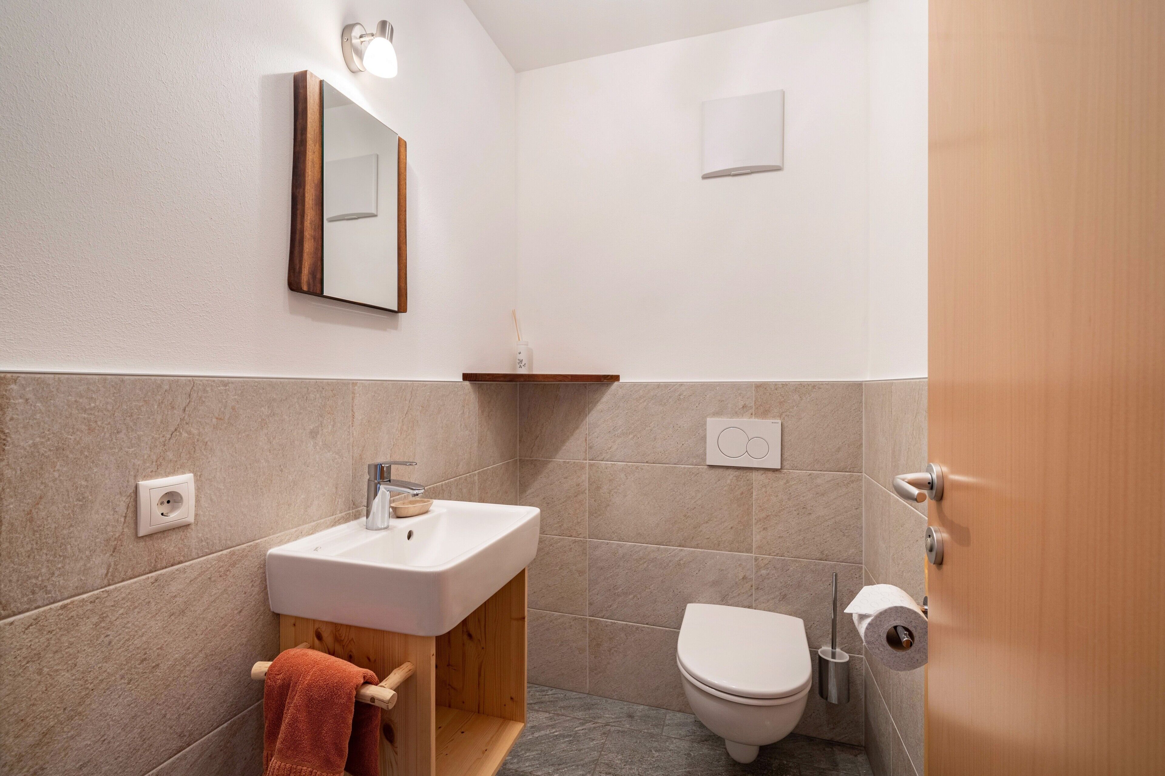 Une salle de bain équipée d’un lavabo, d’un miroir, de toilettes et d’un porte-serviettes.