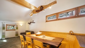 Un comedor con una mesa y sillas de madera, un banco y una viga de techo de madera.