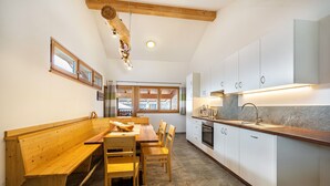 Una cocina con bancos de madera, armarios blancos y suelo de piedra.