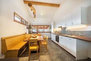 A kitchen with wooden benches, white cabinets, and a stone floor.