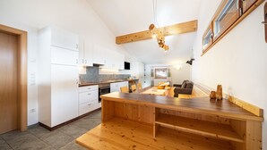 Una cocina moderna con muebles blancos, una mesa de comedor de madera y un techo con vigas a la vista.