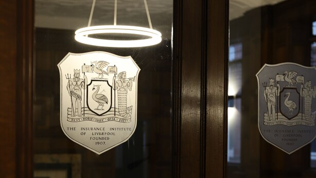 A wooden door with a glass window featuring a coat of arms and a circular emblem. - 16 Queen Avenue (Liverpool)