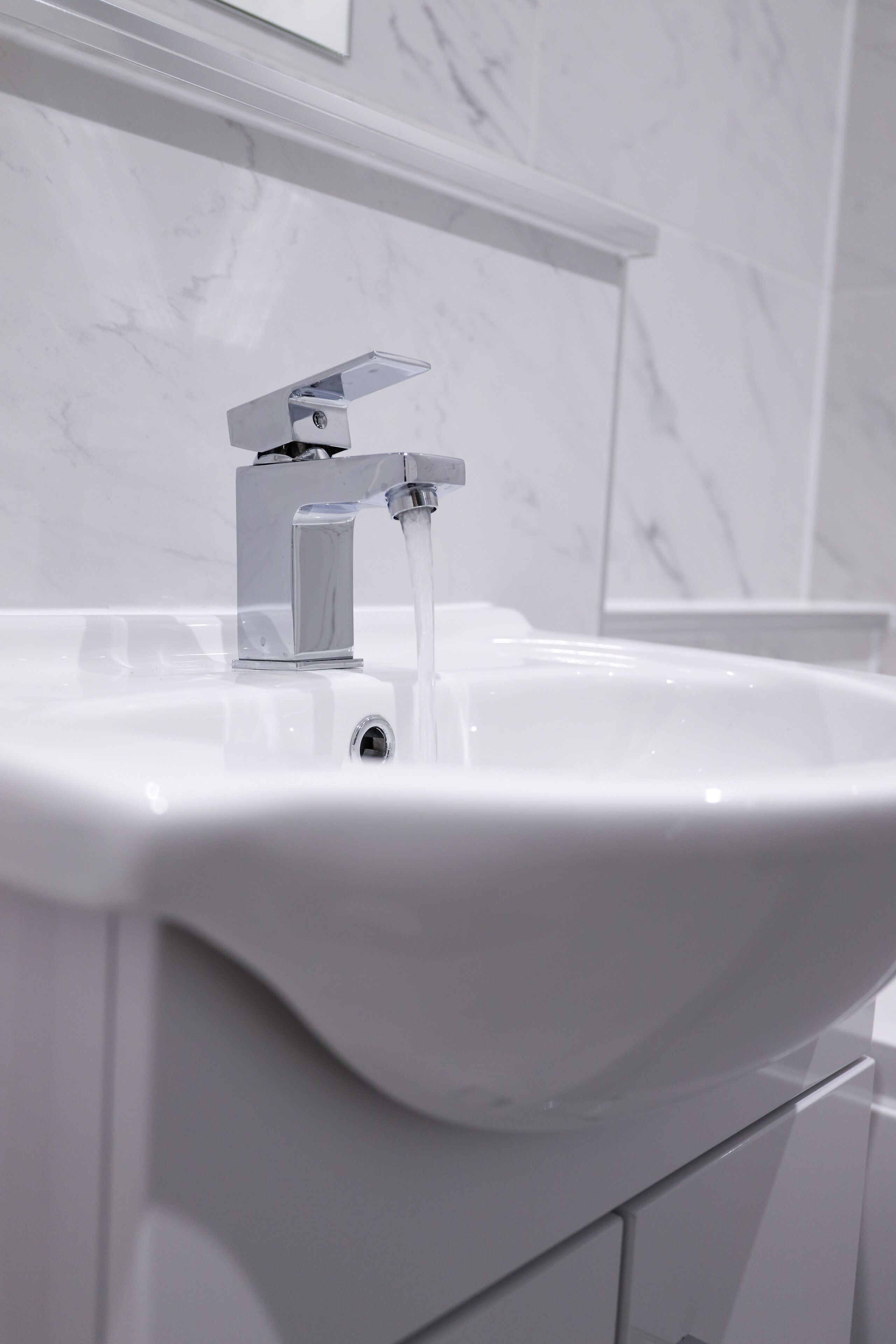 A white bathroom sink with a chrome faucet and a mirror above it.
