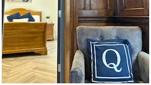 A bedroom with a wooden bed, a nightstand, and a chair with a pillow. - 16 Queen Avenue (Liverpool)