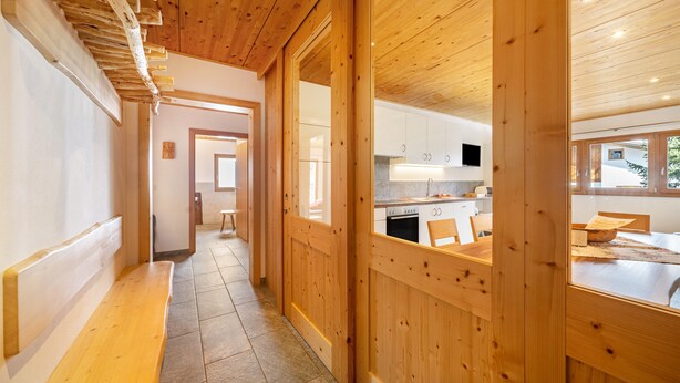 A wooden interior hallway leading to a kitchen with cabinets and a dining area. - Apartment "Enzian" on a Mountain Farm with Balcony (Moos in Passeier)