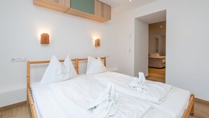 Een moderne hotelkamer met een houten bed en witte beddengoed, plus twee wandlampen.