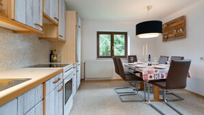 Een moderne keuken met houten kastjes, een eettafel gedekt voor vier personen, en een raam met uitzicht op groen.