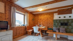 Een houten interieur met een eettafel, stoelen, een bank en een televisietoestel, plus een open haard.