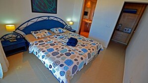 A bedroom with a bed, nightstands, a wall-mounted artwork, a door leading to a bathroom, and a wooden cabinet. - Apartment PLAYA 2 -sea view -2 bedrooms -WiFi -pool (Costa Calma)