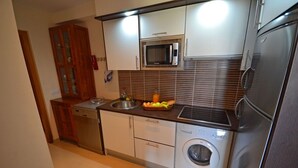 A compact kitchen with white cabinets, a microwave, a stainless steel refrigerator, a washing machine, and a sink. - Apartment PLAYA 2 -sea view -2 bedrooms -WiFi -pool (Costa Calma)
