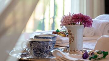 Uma mesa com um vaso de flores, um conjunto de xícaras azul e branco, e uma fita rosa.