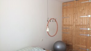 Een slaapkamer met een bed, een grote fitnessbal, een kledingkast en een wandlamp.