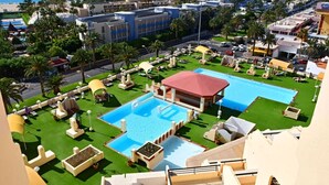 Un complexe hôtelier doté de plusieurs piscines, de vastes pelouses verdoyantes et de palmiers.