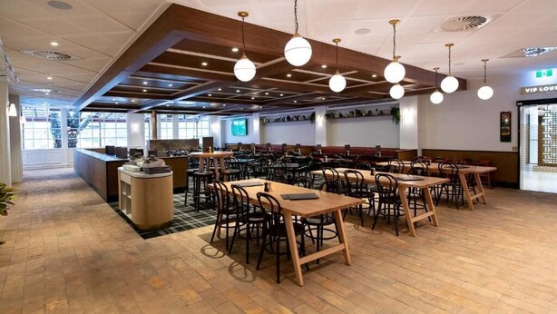 A spacious restaurant with wooden tables and chairs, a counter, and hanging spherical light fixtures. - Wentworth Hotel (Homebush)