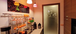 A kitchen with a coffee machine, orange mugs, and a coffee-themed wall art. - Relais Casa Moresca (Terracina)