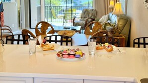 Een eethoek met een tafel gedekt voor twee personen, compleet met een bord vol gebakjes en twee glazen water.