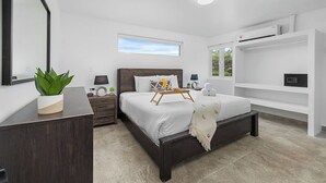 A modern bedroom with a large bed, bedside tables, a dresser, a window, and built-in shelving. - ModernPrivatePoolQuiet3BR2BA Eagle/Palm Beach (Noord)