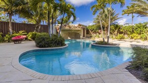 Una piscina rodeada de palmeras y una cerca de madera.